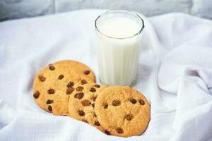 fragranti, gustosi, biscotti fatti in casa con uvetta e un bicchiere di latte fresco sul canovaccio bianco foto