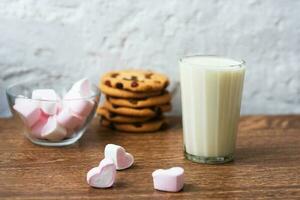 biscotti fatti in casa con latte e marshmallow d'aria su asciugatutto e tavolo di legno. Buongiorno. concetto di colazione foto