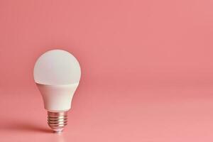 lampadina, copia spazio. concetto minimo di idea di risparmio energetico. sfondo rosa. foto