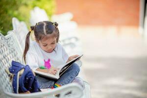 indietro per scuola. asiatico ragazza lettura un' libro. primario scuola studenti dopo classi apprendimento compiti a casa. foto