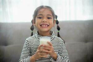 asiatico poco carino ragazzo Tenere un' tazza di latte nel il Casa. sentire contento e godere potabile latte. foto