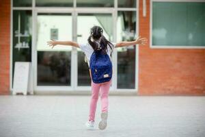 indietro per scuola. carino asiatico bambino ragazza con un' zaino in esecuzione e andando per scuola con divertimento foto