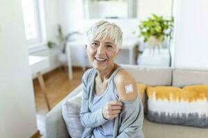 maturo donna con adesivo bendare su sua braccio dopo corona virus vaccino. primo aiuto. medico, farmacia e assistenza sanitaria concetto. foto