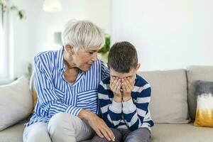 amorevole comprensione vecchio nonna Abbracciare una persona poco pianto ragazzo confortante irritato nipote, anziano cura nonna abbracciare bambino consolante ragazzo nel lacrime, nonne empatia supporto per nipote foto