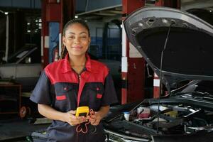 uno nero femmina professionale settore automobilistico meccanico lavoratore controlli un ev auto batteria e ibrido motore a un' Manutenzione box auto, esperto elettrico veicolo servizio, e fissaggio occupazioni auto industria. foto