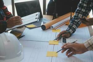 costruzione e struttura concetto di ingegnere o architetto incontro per progetto Lavorando con compagno e ingegneria utensili su modello edificio e planimetria nel Lavorando luogo, contrarre per tutti e due aziende. foto