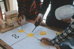 costruzione e struttura concetto di ingegnere o architetto incontro per progetto Lavorando con compagno e ingegneria utensili su modello edificio e planimetria nel Lavorando luogo, contrarre per tutti e due aziende. foto