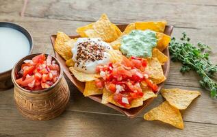 nachos al formaggio con diversi tipi di salsa foto