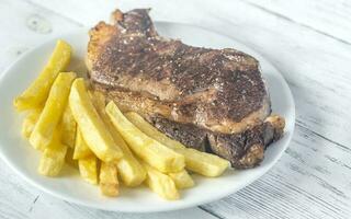 Manzo bistecca con fritte patate su il piatto foto