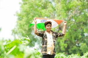 indiano ragazzo Tenere nazionale bandiera nel azienda agricola, contento ragazzo, nazionale bandiera foto