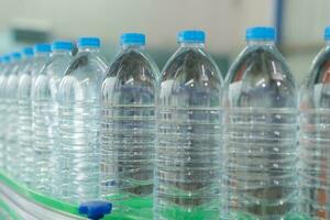 acqua fabbrica - acqua imbottigliamento linea per in lavorazione e imbottigliamento puro minerale acqua in blu bottiglie. selettivo messa a fuoco. foto