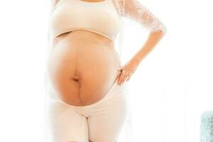 ritratto di un' incinta donna toccante sua grande pancia vicino su, madre, gravidanza, persone e aspettativa. donna Tenere grande incinta stomaco foto