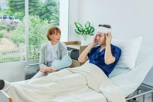 il paziente ha un' mal di testa mentre dire bugie nel il ospedale camera con garza bendare avvolto in giro testa. foto