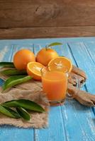 arancia fresca e un bicchiere di succo d'arancia su uno sfondo di tavolo in legno foto