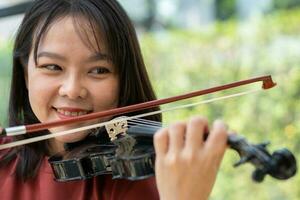 un attraente donna apprendimento musicista giochi il violino a casa. compositore la creazione di canzoni con corda strumenti. sognante violinista dita urgente stringhe su violino foto