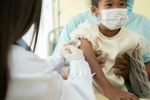 asiatico medico utente siringa ago per iniezione vaccinare, africano americano bambini siamo essere covid vaccinati per prevenzione coronavirus e influenza. concetto di immunizzazione a partire dal inoculazione foto