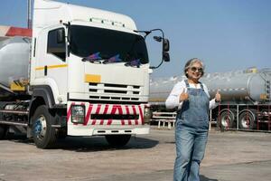 attività commerciale proprietario in piedi nel davanti di olio camion dopo l'esecuzione un' pre-viaggio ispezione su un' camion. concetto di preventivo Manutenzione. foto