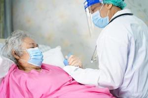 il medico aiuta e controlla la paziente asiatica anziana o anziana anziana che indossa una maschera facciale in ospedale per proteggere l'infezione covid-19 coronavirus. foto