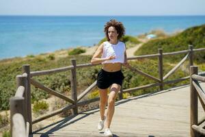attivo donna nel abbigliamento sportivo jogging vicino oceano foto