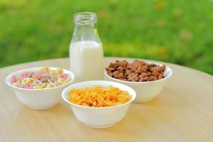 ciotole con diversi tipi di prodotti a base di cereali per la colazione, ciotole bianche con il pasto mattutino foto