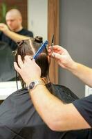 maschio stilista taglio il capelli di femmina cliente nel professionale bellezza salone. foto