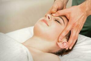 bella giovane caucasico donna ricevente un' testa massaggio di un' maschio massaggio terapista nel un' bellezza salone. foto
