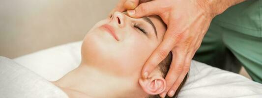 bella giovane caucasico donna ricevente un' testa massaggio di un' maschio massaggio terapista nel un' bellezza salone. foto