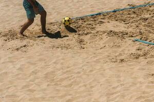 vicino su di non identificabile uomo giocando footvolley su il spiaggia foto