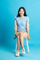 ritratto di sorridente asiatico donna in posa su blu sfondo foto