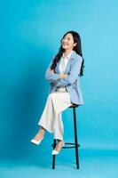 asiatico donna d'affari ritratto seduta su sedia, isolato su blu sfondo foto