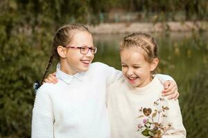 Due studentesse camminare, abbraccio e ridere dopo scuola nel il parco. indietro per scuola concetto foto