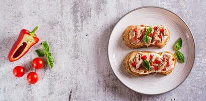 crostini con in scatola tonno, crema formaggio, peperoni e erbe aromatiche su un' piatto superiore Visualizza ragnatela bandiera foto