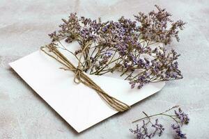 un' mazzo di secco fiori nel un' leggero Busta legato con un' corda su un' strutturato sfondo. saluto romantico carta foto
