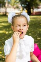 carino poco scolara mangiare pepite appetitoso su un' picnic nel il parco. scuola pasti. verticale Visualizza foto