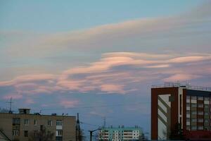 lenticolare nuvole nel il città sopra il tetti di grattacielo edifici a tramonto. bellissimo cielo foto