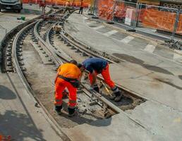 lavoratori a opera mentre sistenabo il tram rotaie foto