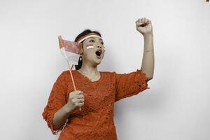 un' giovane asiatico donna con un' contento riuscito espressione indossare rosso kebaya e fascia per capelli isolato di bianca sfondo. dell'Indonesia indipendenza giorno concetto. foto