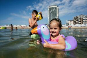 poco ragazza nuotate nel il mare con un gonfiabile squillare piace tucano. foto