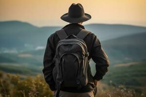 indietro Visualizza di giovane uomo con zaino e cappello in piedi su superiore di il montagna foto