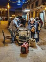 uomo che vende castagne cotte al pubblico in centro città foto