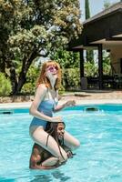 afroamericano uomo e bianca donna giocando nel un' piscina. foto