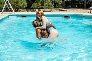afroamericano uomo e bianca donna giocando nel un' piscina. foto