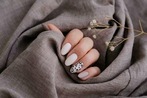 un' donna di mano con un' bellissimo manicure detiene un' beige tessuto e fiori . autunno tendenza, beige colore lucidatura con leopardo modello su Chiodi con gel polacco, Gommalacca. foto