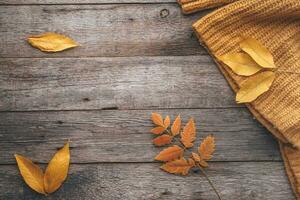 autunno le foglie e a maglia maglione su vecchio di legno sfondo . copia spazio foto