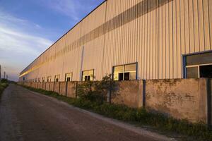 industriale sera luce del sole riflettendo su il industriale magazzino contro il blu cielo paesaggio Visualizza foto