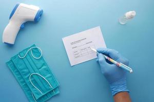 scheda di registrazione delle vaccinazioni, disinfettante per le mani e maschera su sfondo colorato foto