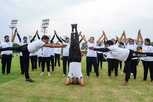 nuovo delhi, India, giugno 21, 2023 - gruppo yoga esercizio sessione per persone a yamuna gli sport complesso nel delhi su internazionale yoga giorno, grande gruppo di adulti frequentando yoga classe nel cricket stadio foto