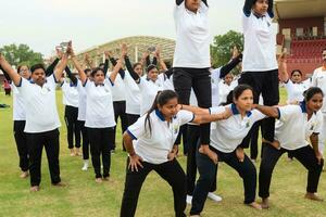 nuovo delhi, India, giugno 21, 2023 - gruppo yoga esercizio sessione per persone a yamuna gli sport complesso nel delhi su internazionale yoga giorno, grande gruppo di adulti frequentando yoga classe nel cricket stadio foto