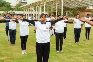 nuovo delhi, India, giugno 21, 2023 - gruppo yoga esercizio sessione per persone a yamuna gli sport complesso nel delhi su internazionale yoga giorno, grande gruppo di adulti frequentando yoga classe nel cricket stadio foto