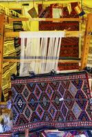 un' tradizionale tappeto essere intrecciata su un' tappeto verticale telaio, mostrando lana mucchio sotto tensione, fondazione, ordito e trama. foto